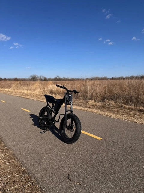 Riding Times Z8 electric off-road eBike on a highway with brown grass in the background, highlighting the best electric off-road eBikes.